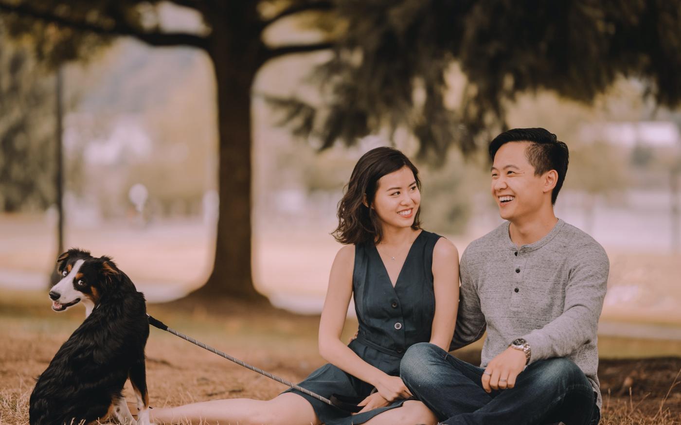 Happy couple sitting in a park with their dog