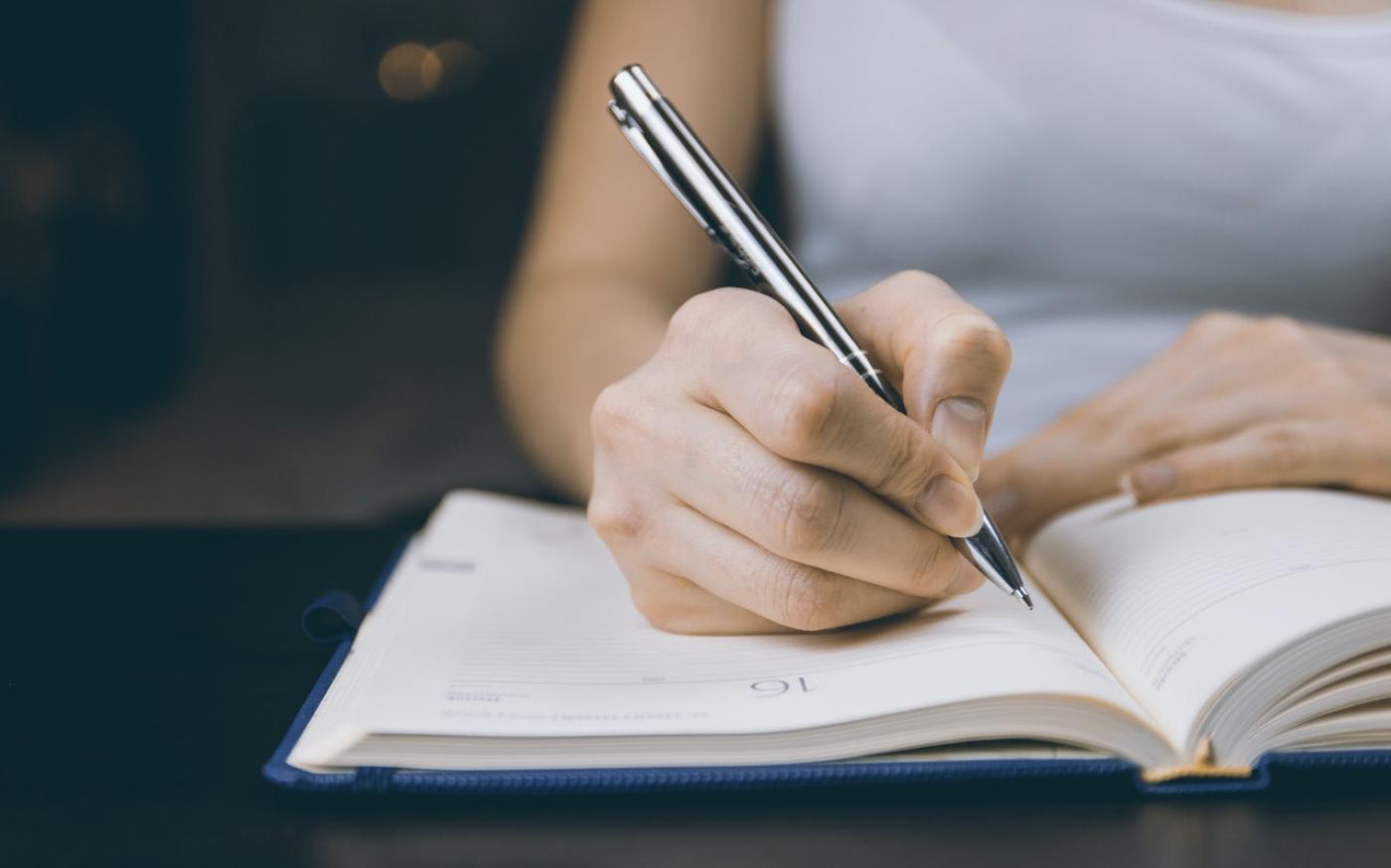 Woman writing in a paper planner with a pen